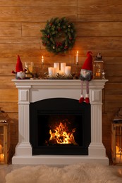 Photo of Cute Christmas gnomes and festive decorations on fireplace in room