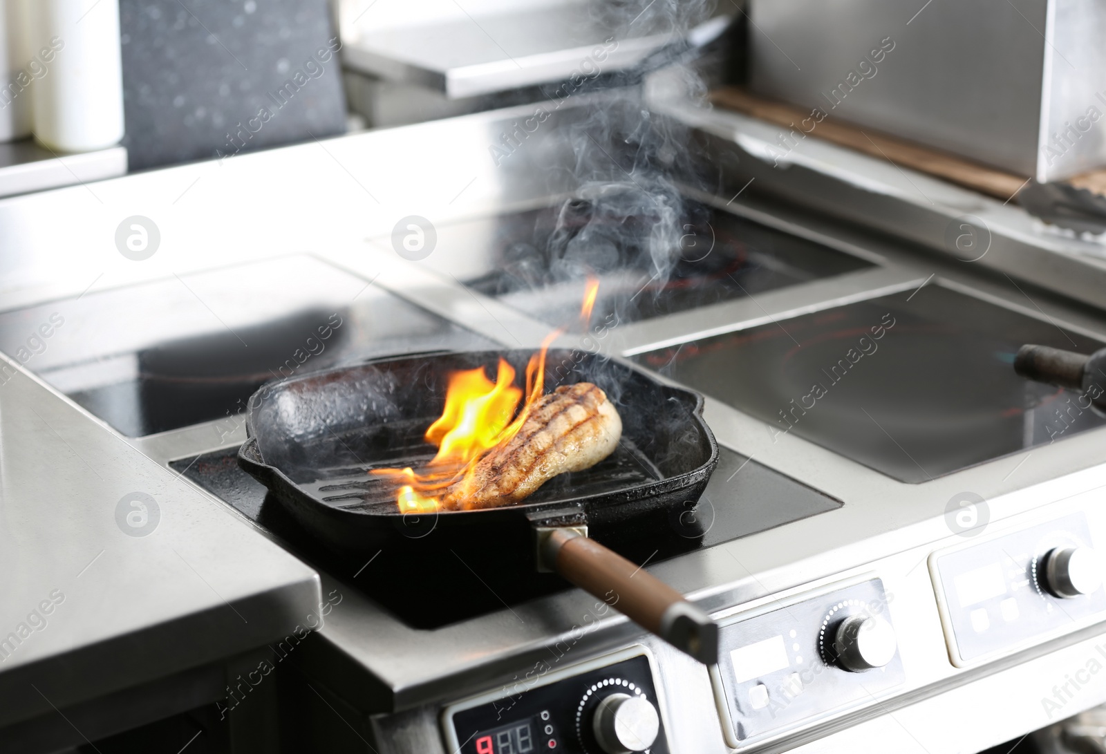 Photo of Cooking meat with burning flame in restaurant kitchen