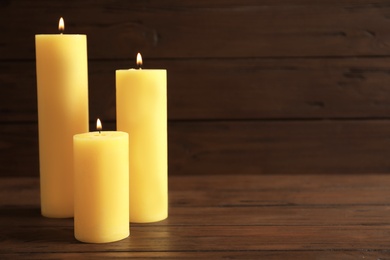 Wax yellow candles burning on wooden table