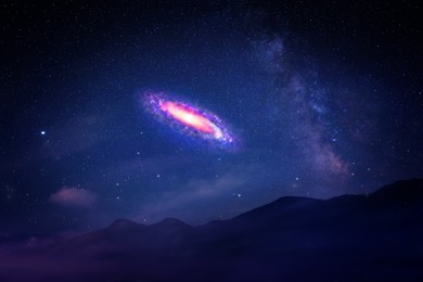 Beautiful spiral galaxy in starry sky over mountains