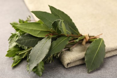 Aromatic bay leaves and different herbs on light gray table, closeup