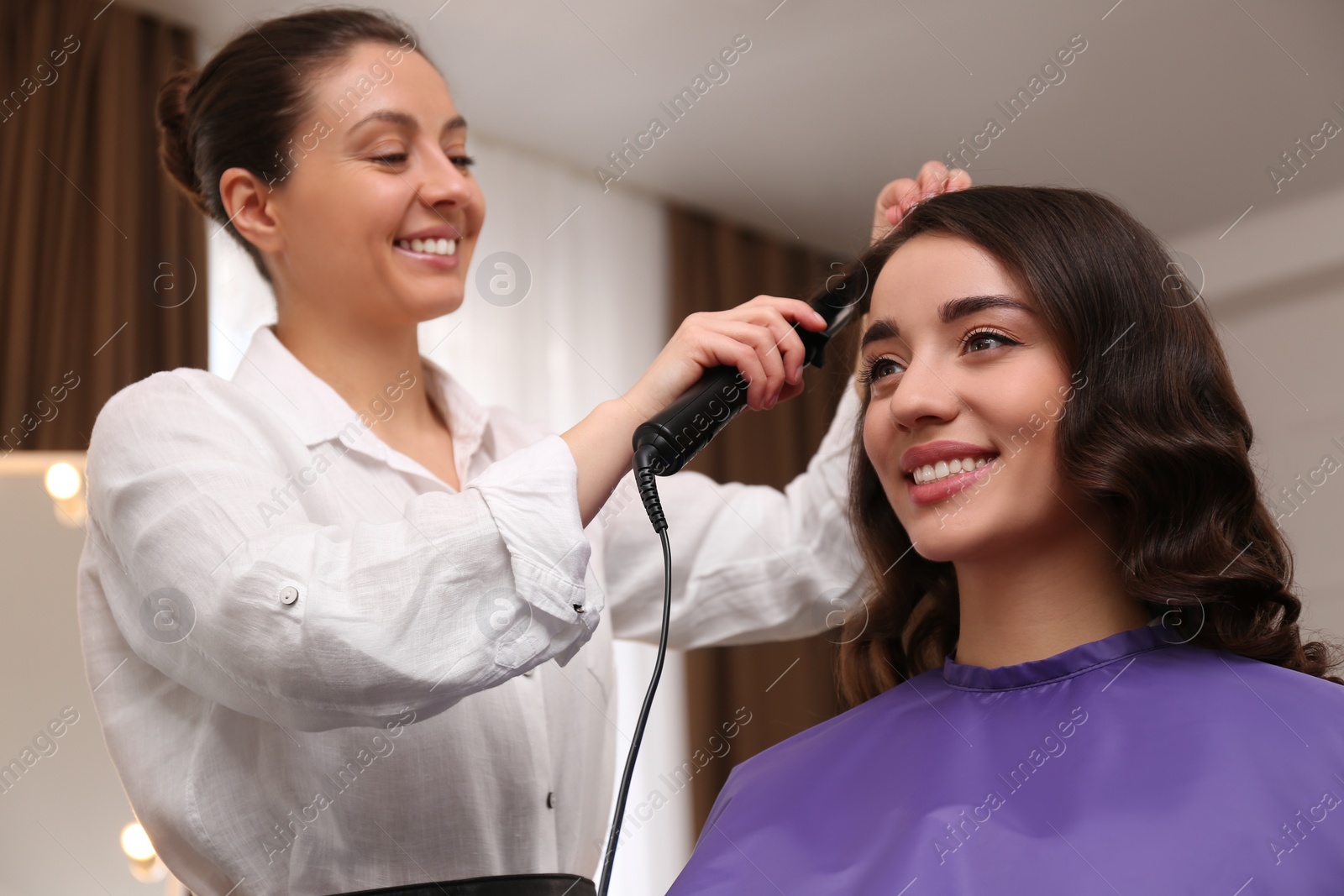 Photo of Stylist working with client in salon, making hairstyle