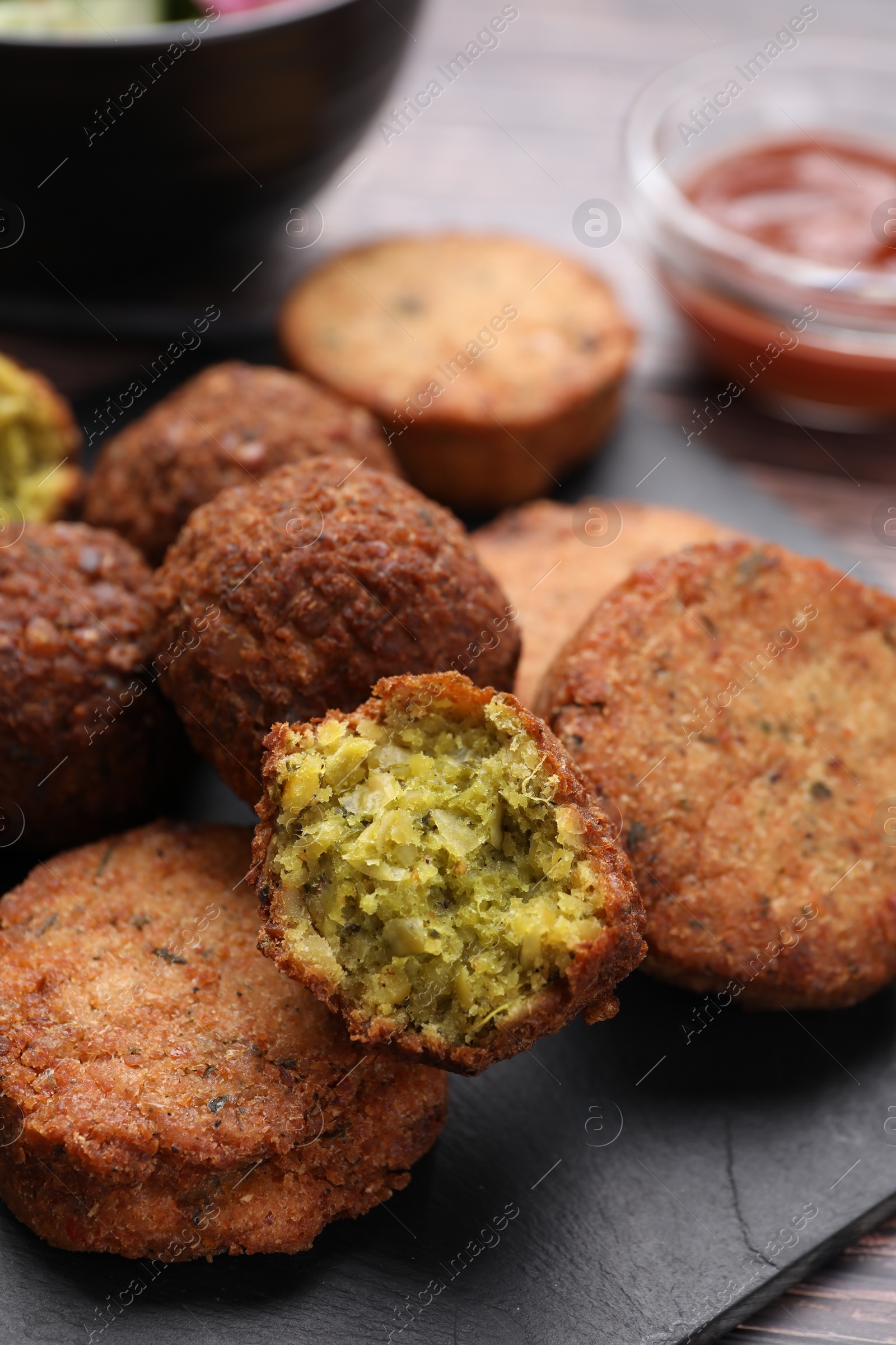 Photo of Delicious vegan cutlets and falafel balls on slate board, closeup