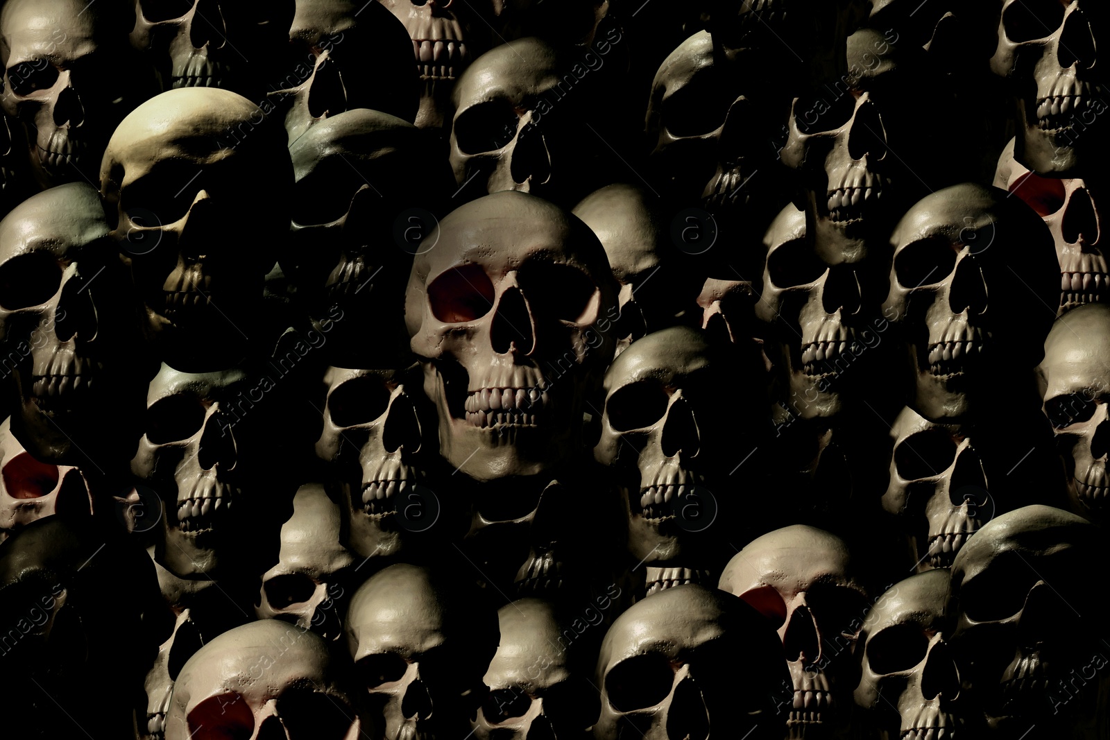 Image of Many scary human skulls as background. Collage design