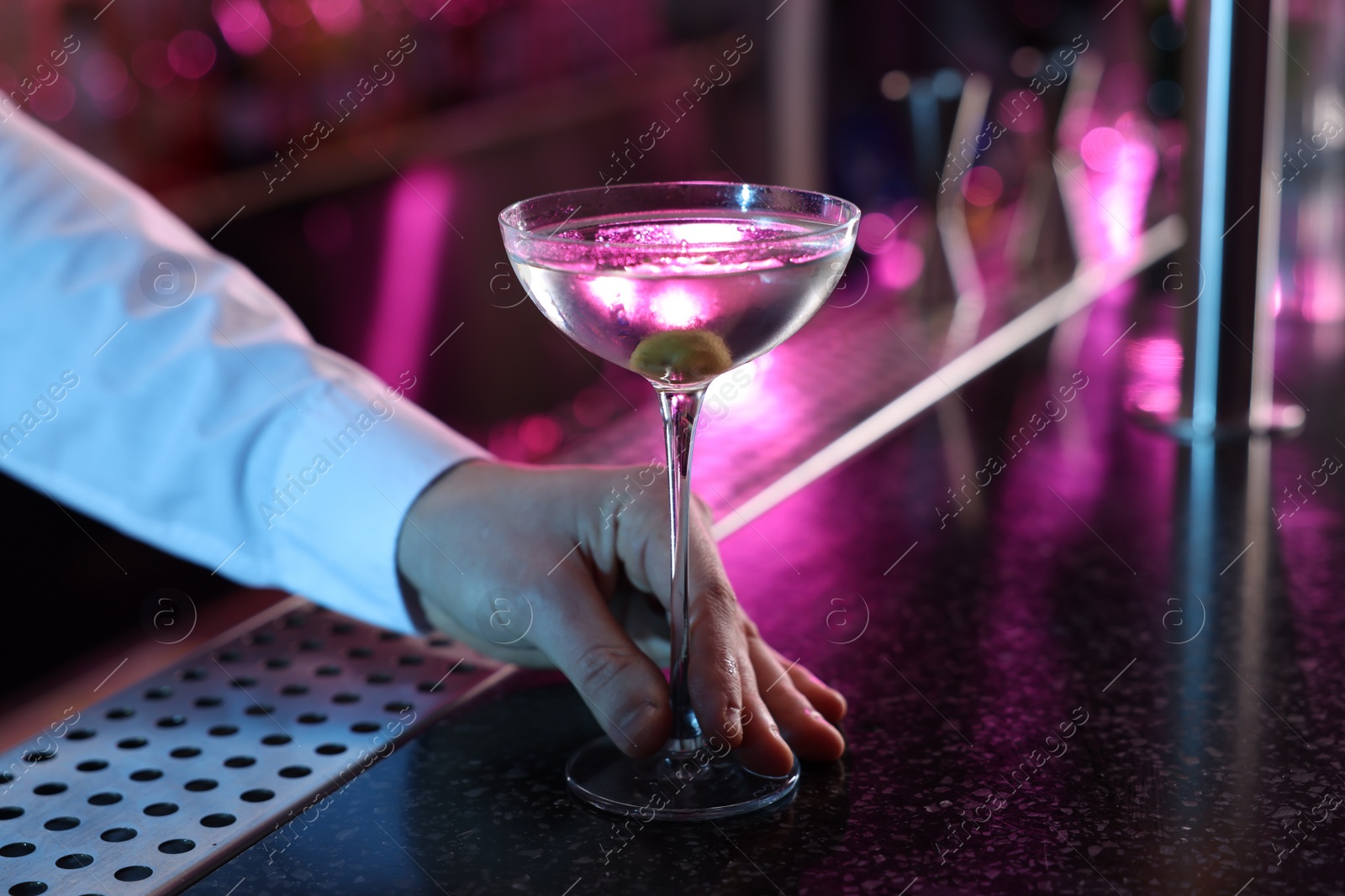 Photo of Bartender with fresh Martini cocktail at bar counter, closeup