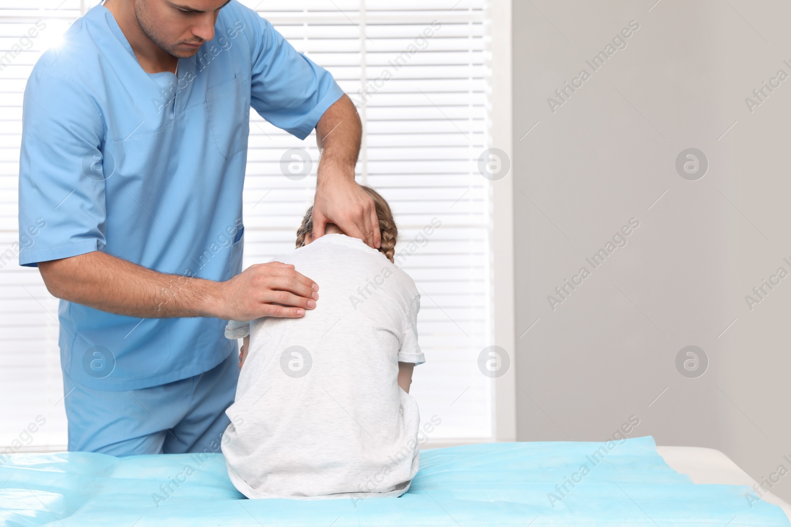 Photo of Orthopedist examining child's back in clinic. Scoliosis treatment