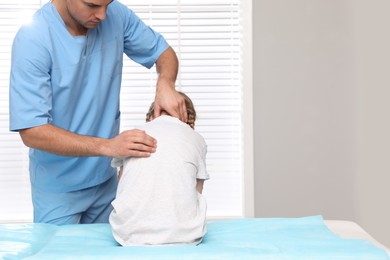 Photo of Orthopedist examining child's back in clinic. Scoliosis treatment