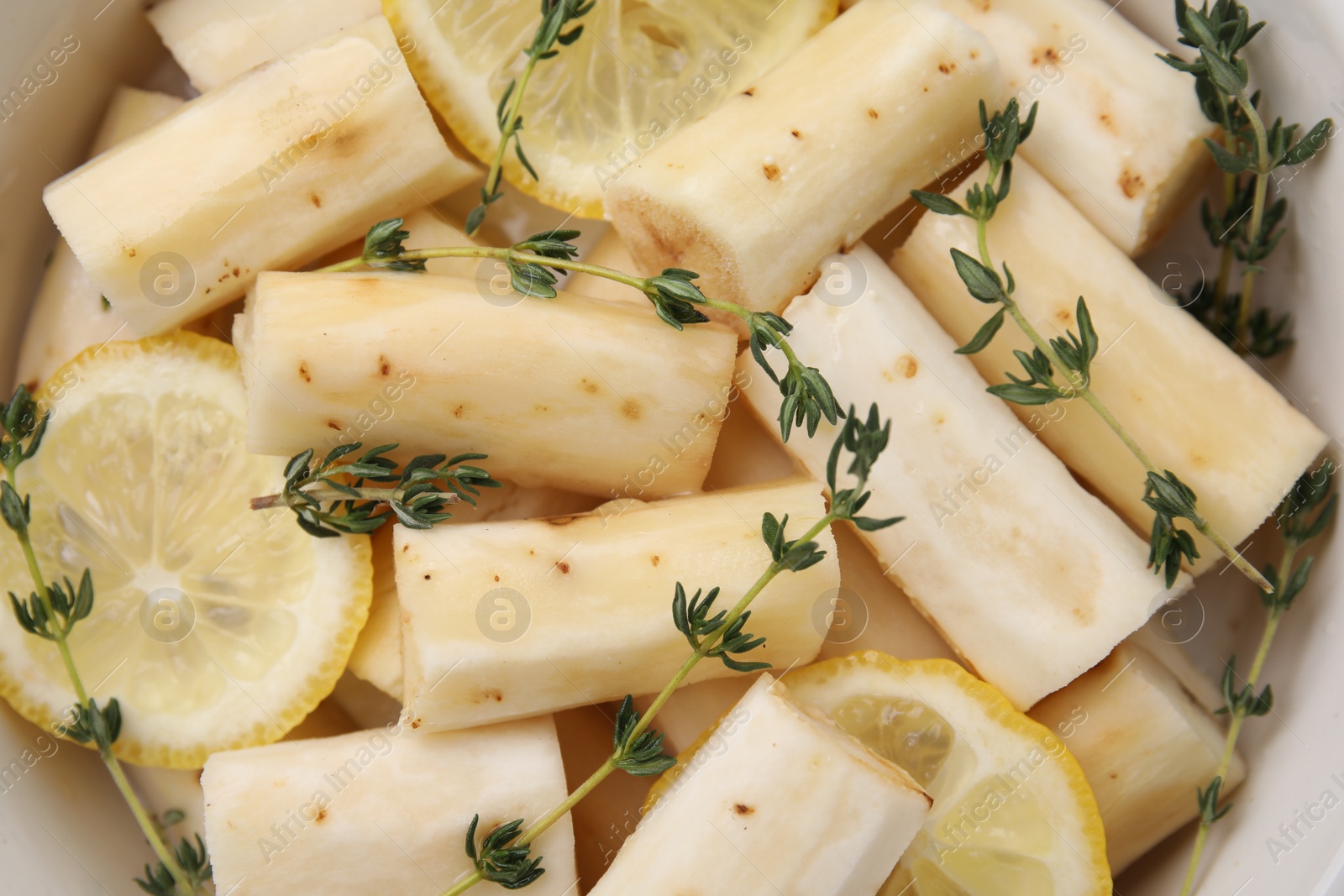 Photo of Dish with raw salsify roots, lemon and thyme, top view