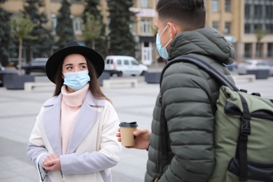 Couple in medical face masks walking outdoors. Personal protection during COVID-19 pandemic