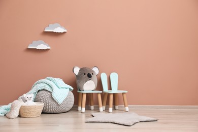 Photo of Child's toys, pouf and chairs near pink wall indoors. Interior design
