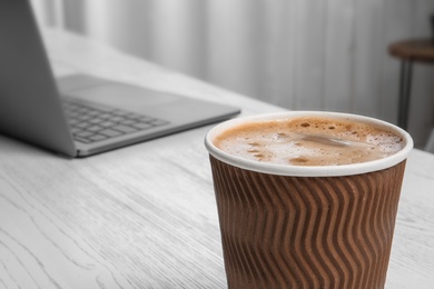 Cardboard cup with aromatic coffee on table. Space for text