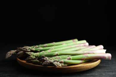 Photo of Fresh raw asparagus on black table, closeup. Space for text