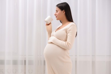 Photo of Beautiful pregnant woman with cup of drink indoors