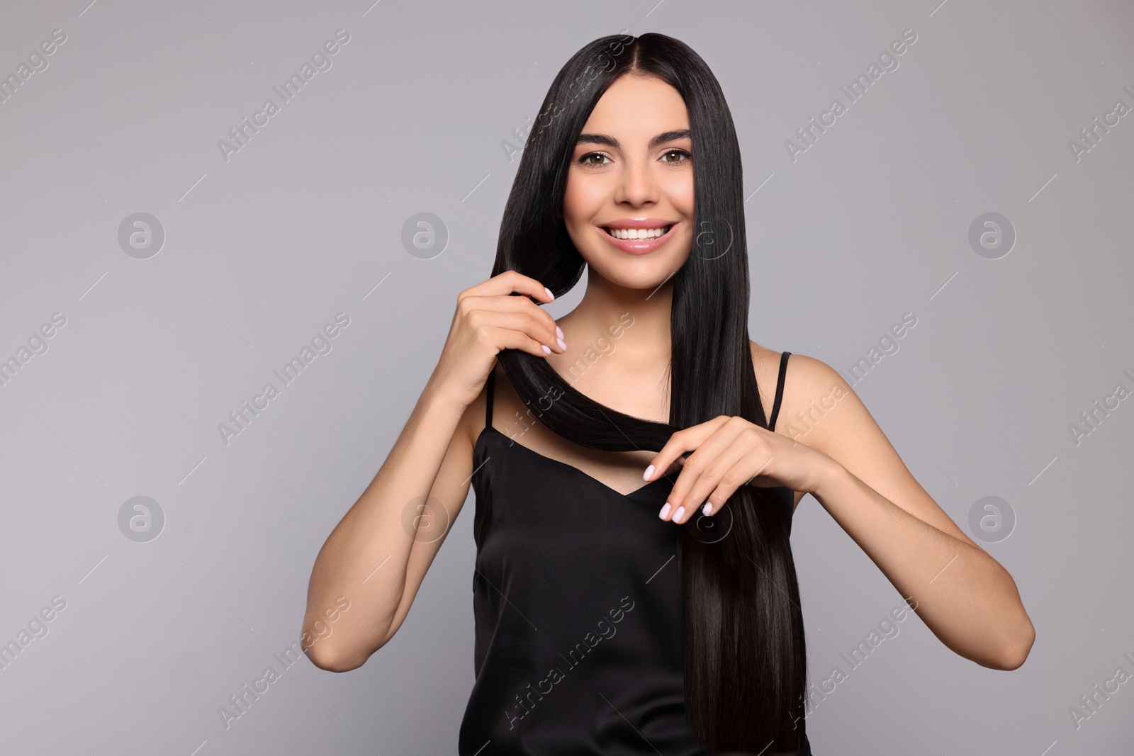 Photo of Portrait of beautiful young woman with healthy strong hair on light grey background, space for text