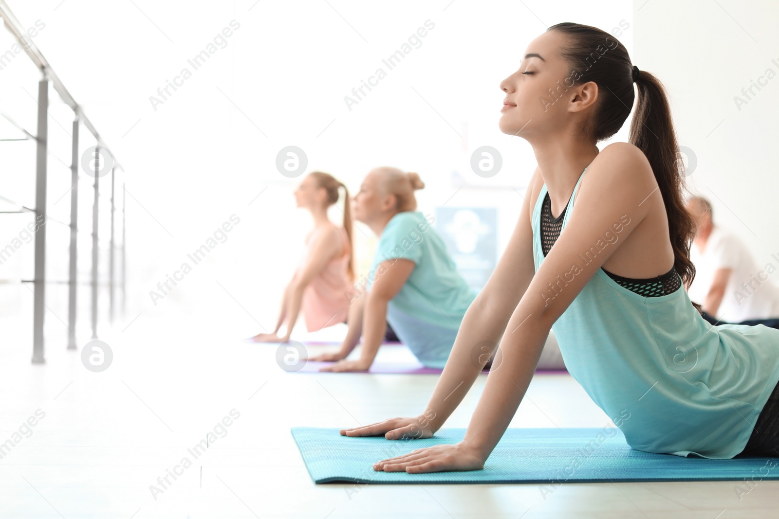 Photo of Group of people in sportswear practicing yoga indoors