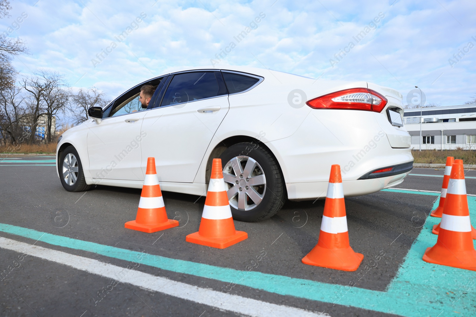 Photo of Young man in car on test track with traffic cones. Driving school