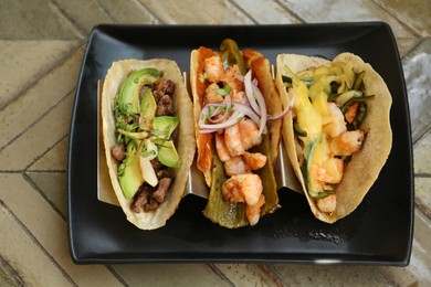 Delicious tacos with shrimps and vegetables on table, above view