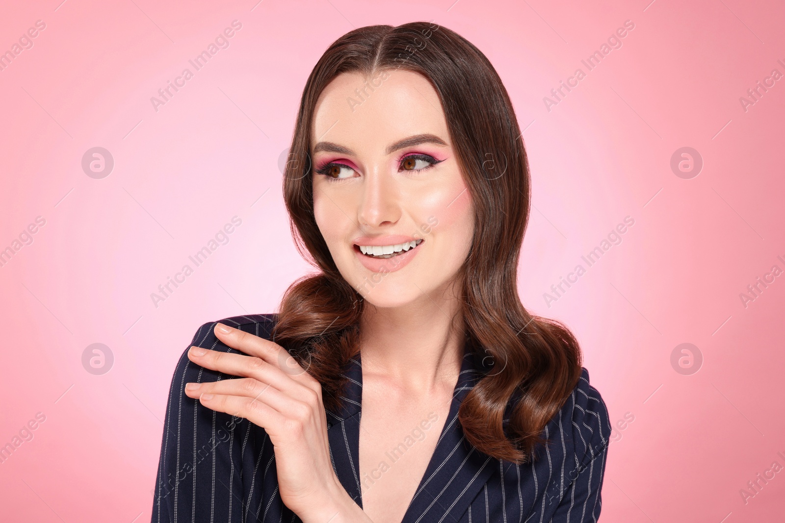 Photo of Portrait of beautiful young woman with makeup and gorgeous hair styling on pink background