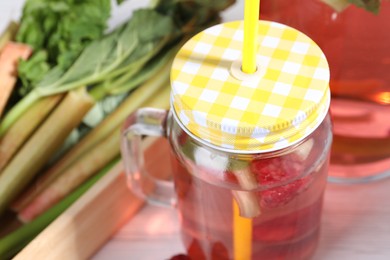 Photo of Mason jar of tasty rhubarb cocktail on table, closeup