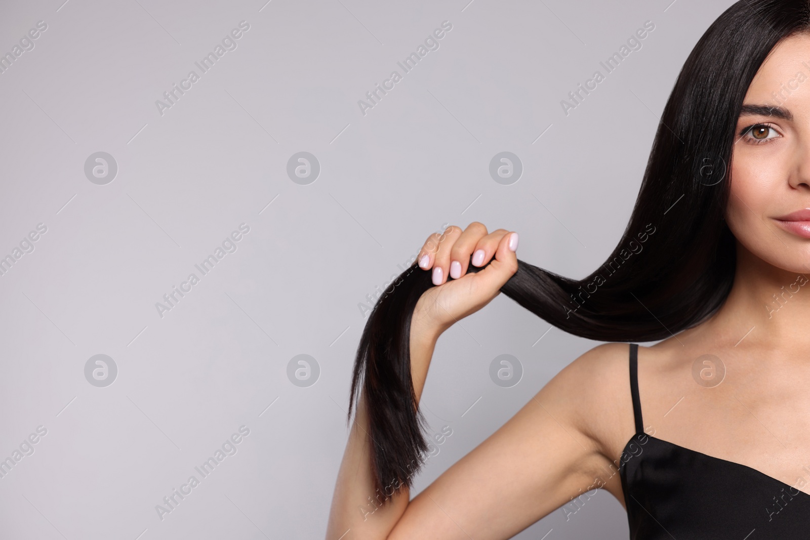 Photo of Portrait of beautiful young woman with healthy strong hair on light grey background, closeup. Space for text