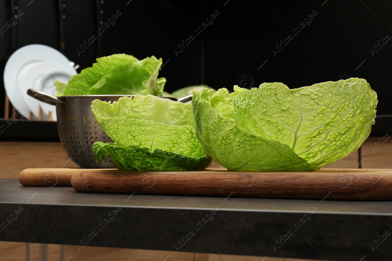 Photo of Fresh Savoy cabbage leaves on black table in kitchen