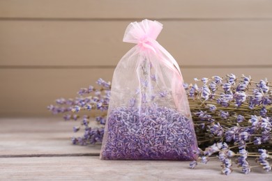 Photo of Scented sachet and dried lavender flowers on wooden table, closeup
