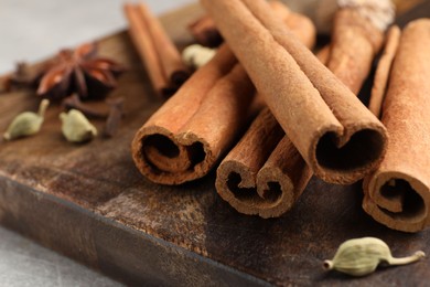 Board with cinnamon sticks and cardamon pods on light table, closeup