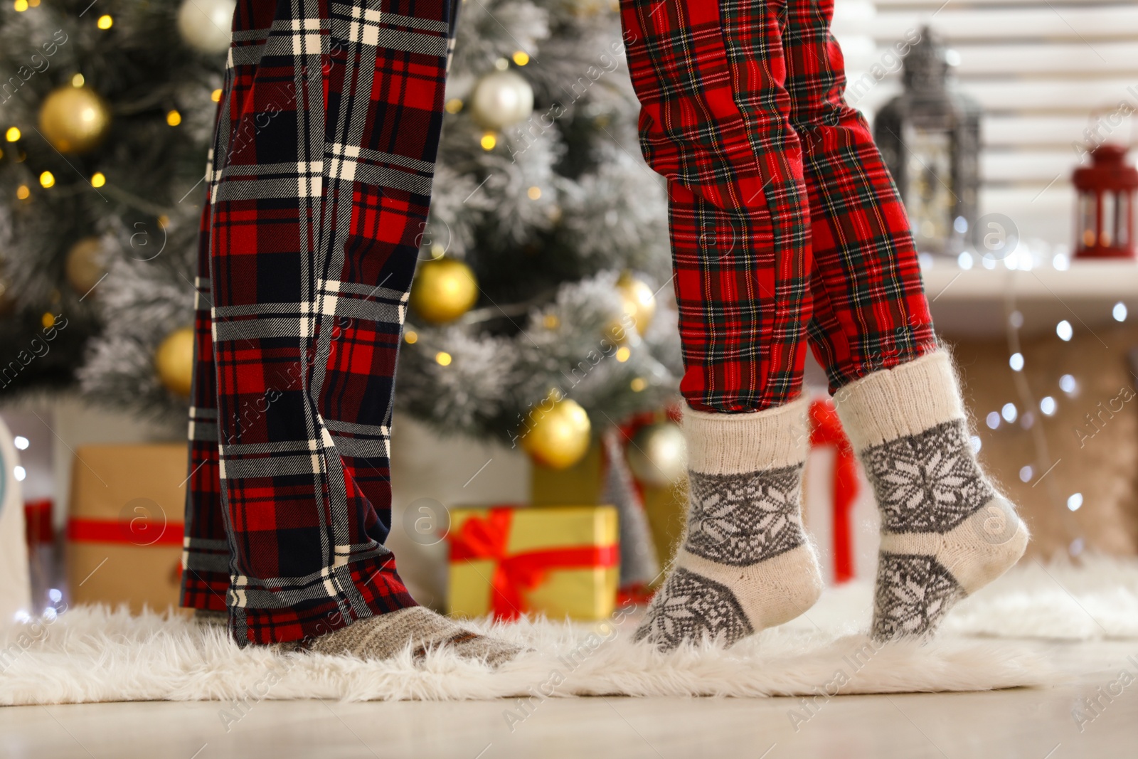 Photo of Young couple near Christmas tree at home, closeup