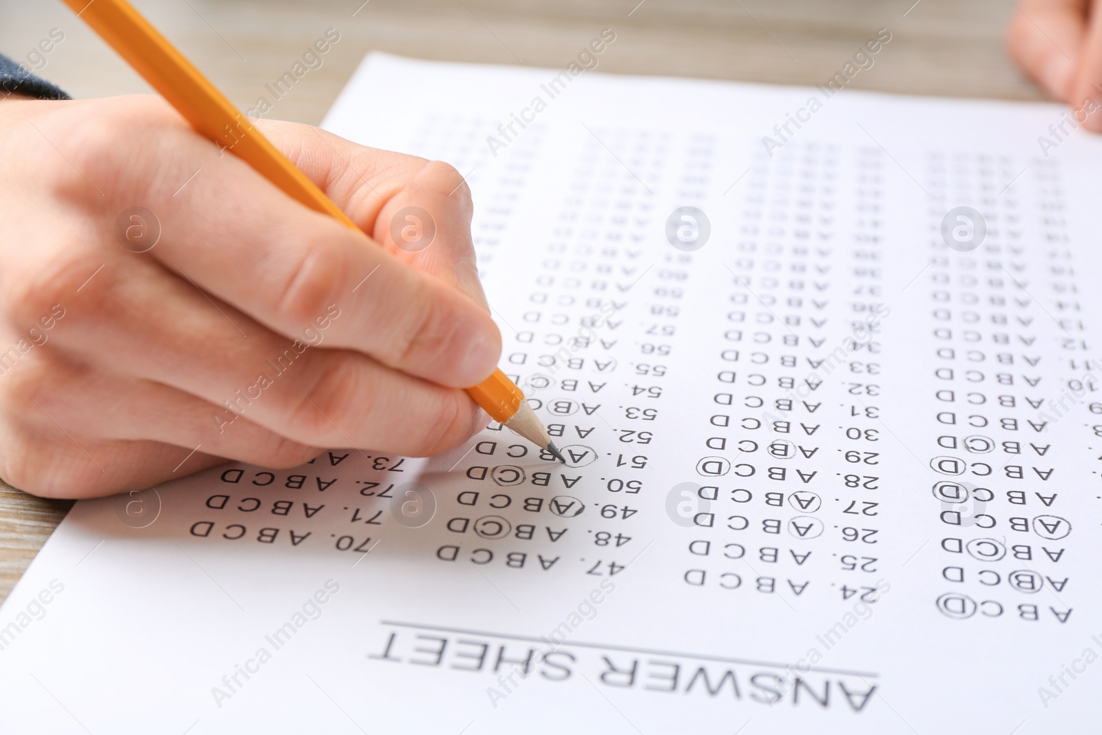 Photo of Student filling answer sheet at table, closeup