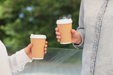 Photo of Women holding takeaway paper cups outdoors, closeup. Coffee to go