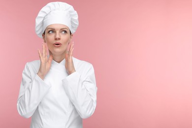 Photo of Confused woman chef in uniform on pink background, space for text