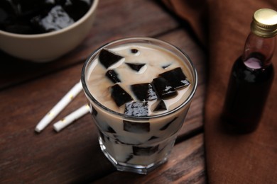 Photo of Glass of milk with grass jelly on wooden table, closeup