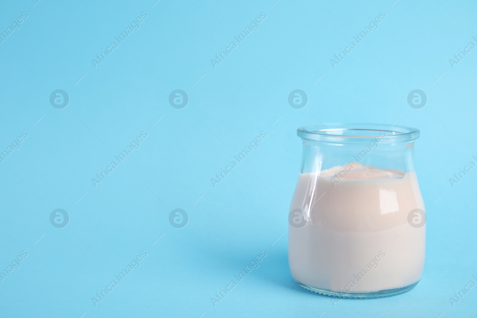 Photo of Tasty organic yogurt on light blue background. Space for text