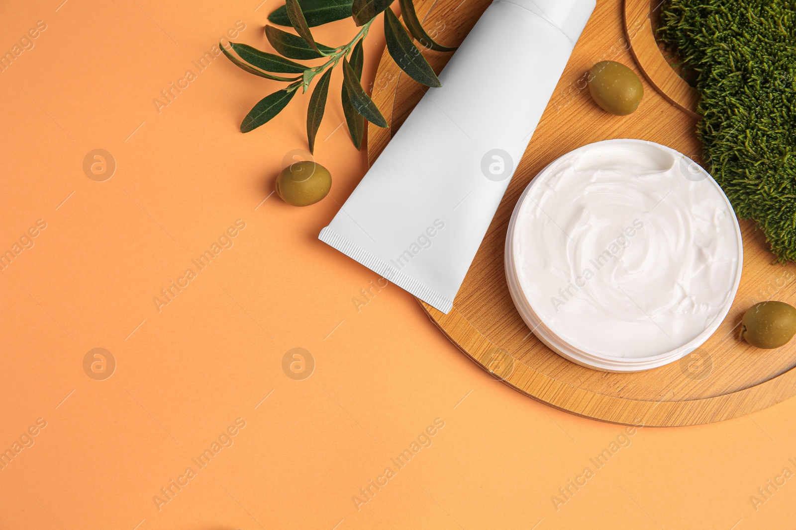 Photo of Flat lay composition with different cosmetic products and olives on pale orange background. Space for text