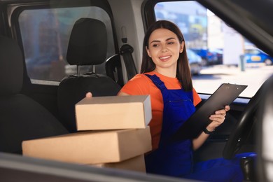 Courier with clipboard checking packages in car