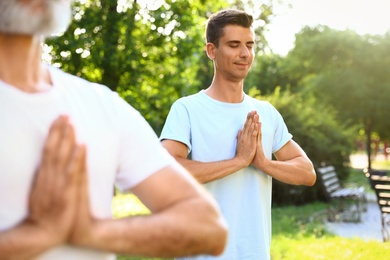 Photo of Men practicing morning yoga in sunny park