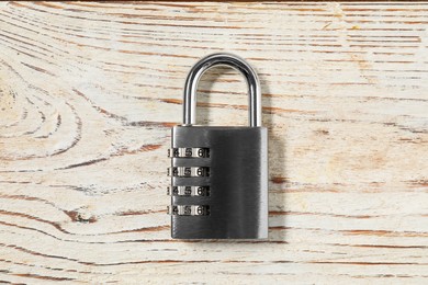 Photo of One steel combination padlock on light wooden table, top view