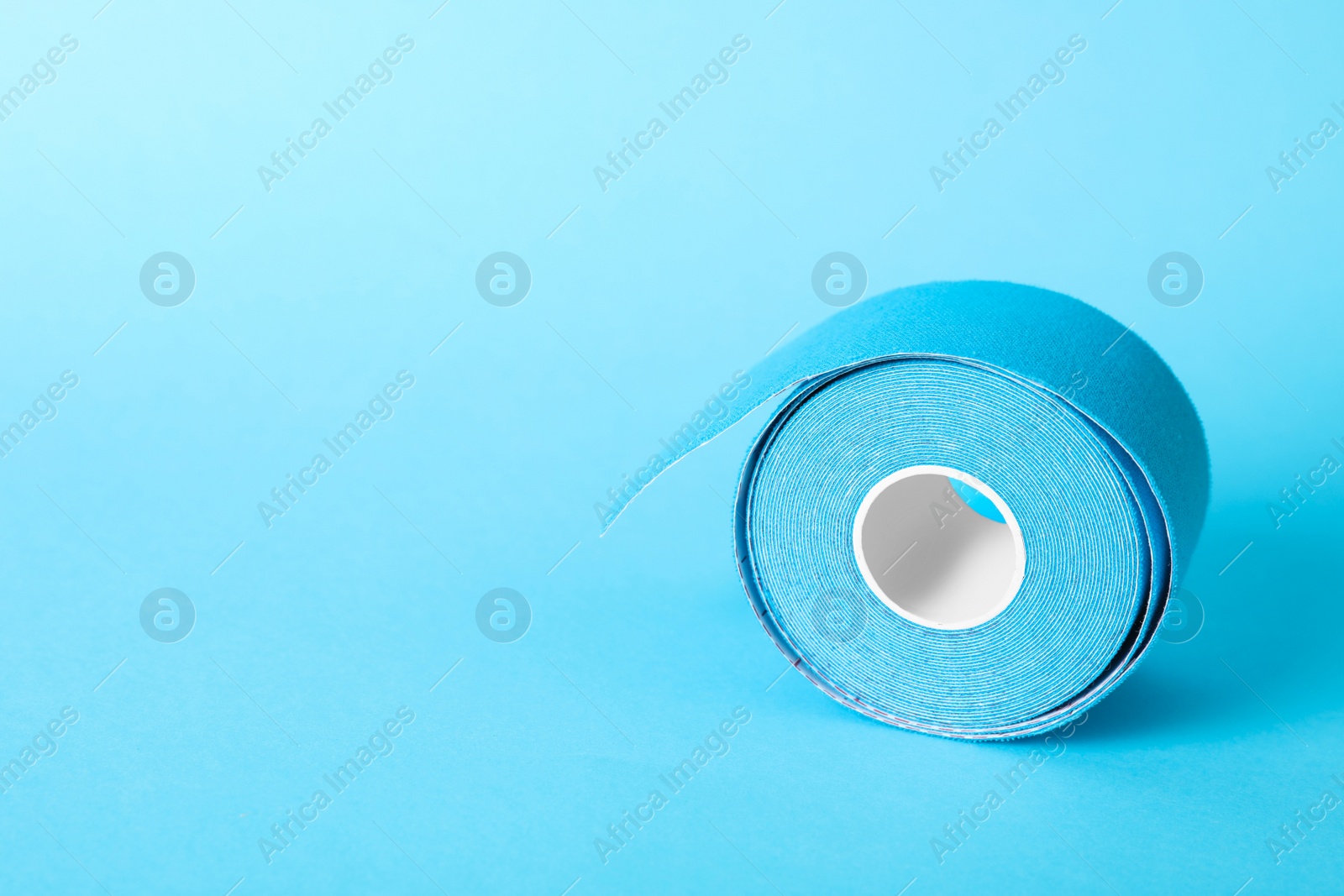 Photo of Bright kinesio tape in roll on light blue background. Space for text