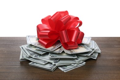 Photo of Pile of dollar bills with red bow on wooden table against white background