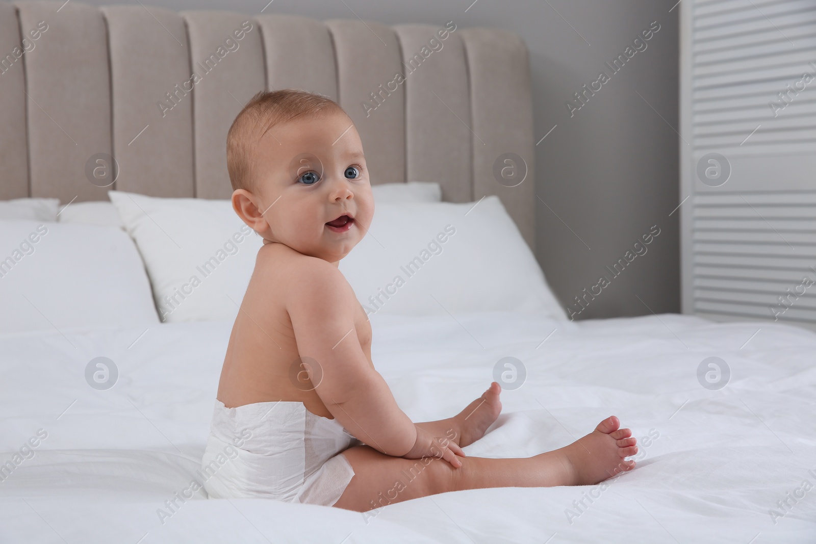 Photo of Cute baby in dry soft diaper on white bed at home