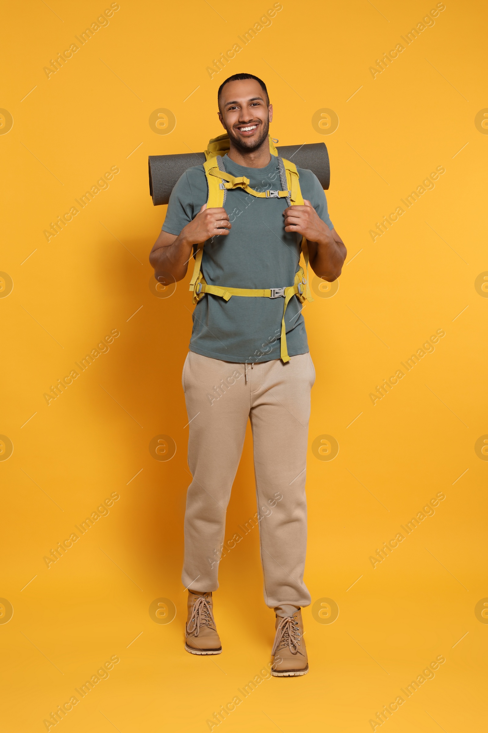 Photo of Happy tourist with backpack on yellow background