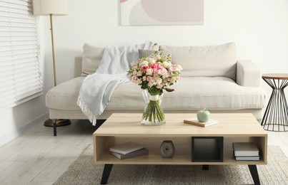 Beautiful bouquet of fresh flowers in vase on wooden coffee table indoors