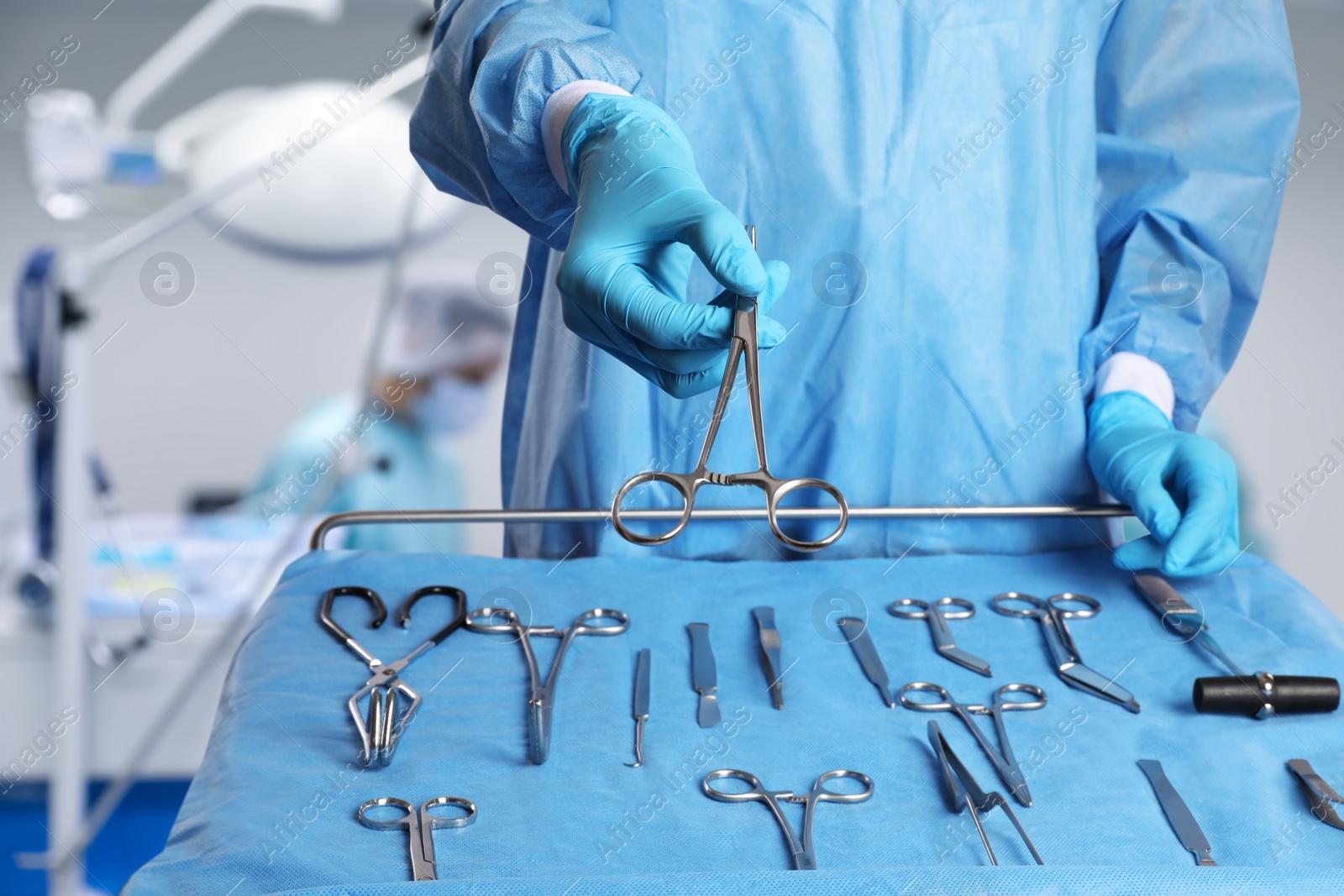 Image of Nurse near table with different surgical instruments in operating room, closeup