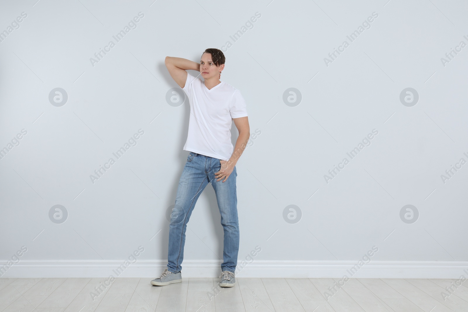 Photo of Young man in stylish jeans near light wall