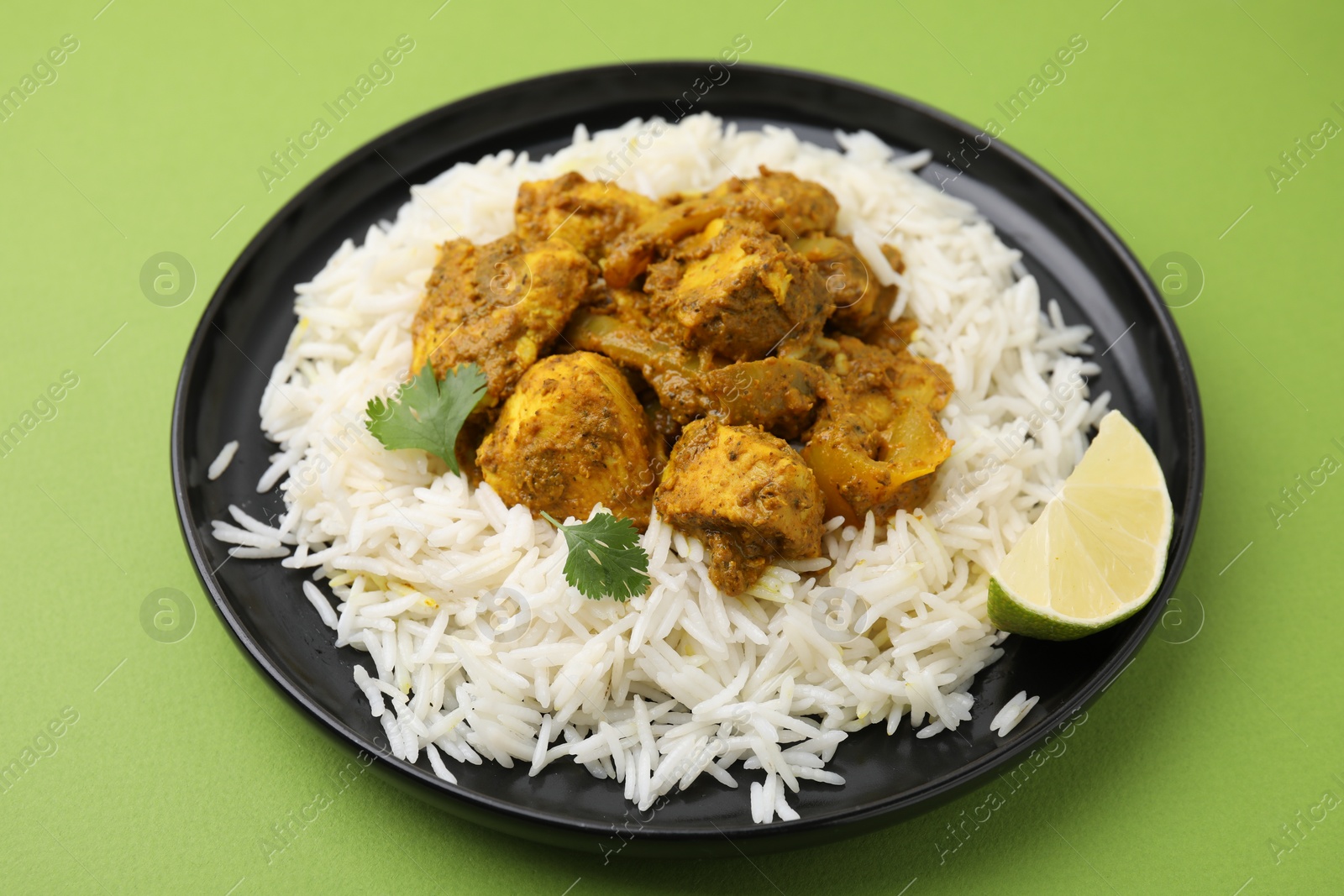 Photo of Delicious chicken curry with rice on green background, closeup