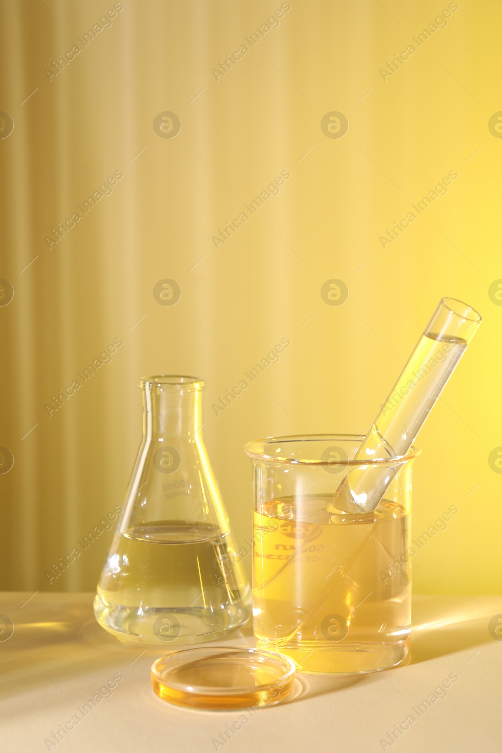 Photo of Laboratory analysis. Different glassware on table against yellow background