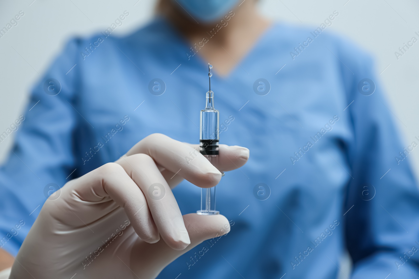 Photo of Doctor holding syringe with COVID-19 vaccine on light background, closeup