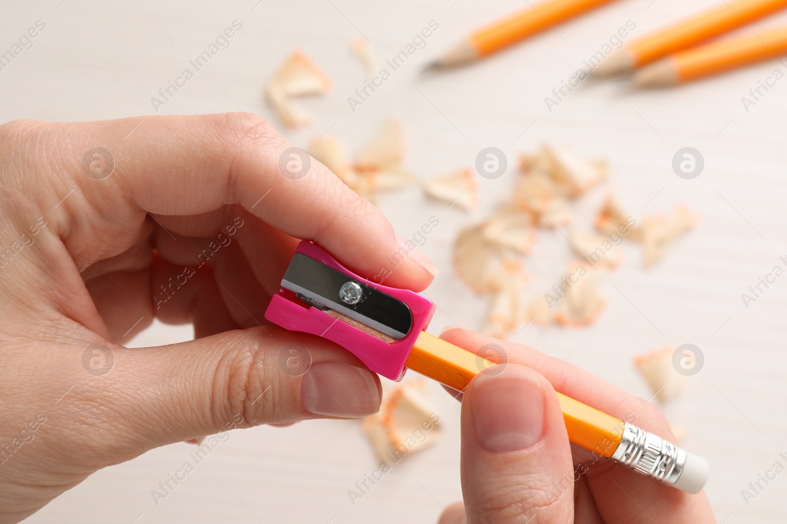 Photo of Woman sharpening pencil at light table, closeup