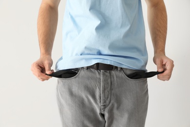 Photo of Man showing empty pockets on light background