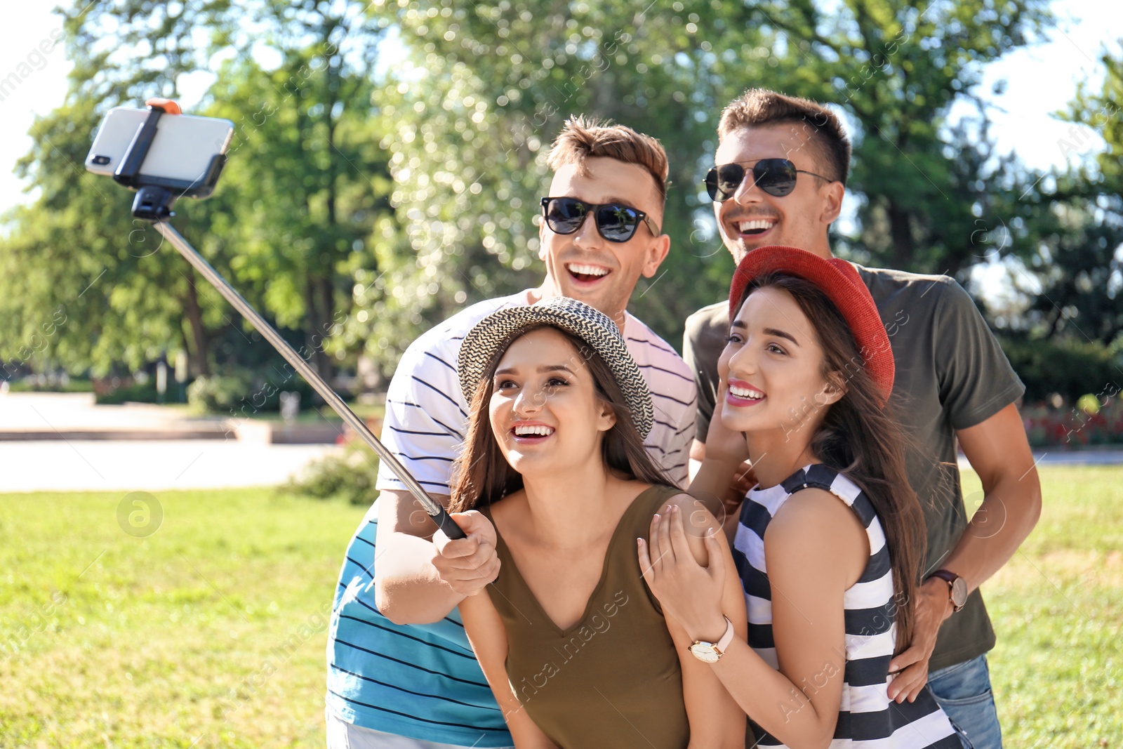 Photo of Group of young people taking selfie with monopod outdoors